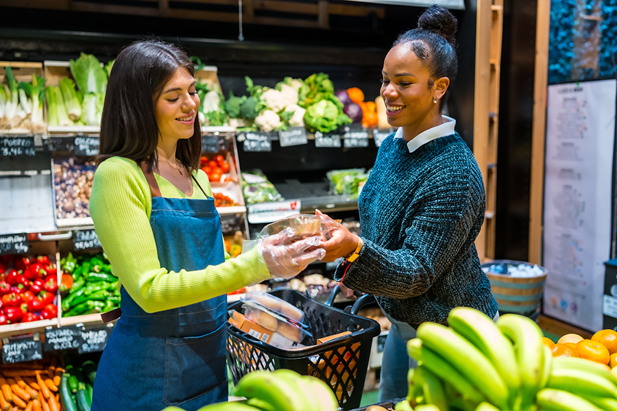 Associate helps a customer in a grocery store aisle.